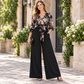 Eleganblomstret Jumpsuit med V-utringning, Vidbeinte Bukser, Midjebånd og Kruslete 3/4-ermer